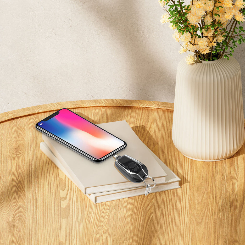 Smartphone on a book with a remote control and vase of flowers on a wooden table