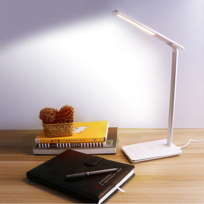 Desk lamp on a wooden surface with books and a notebook