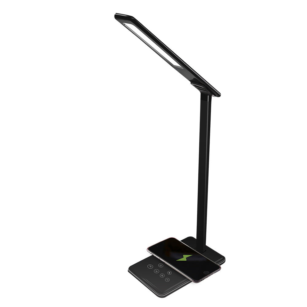 Black LED desk lamp with wireless charging pad on a white background
